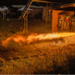 rocket firing on a test stand, bright flames emerging from the engine horizontally