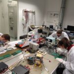 multiple people working on electronics in a clean room