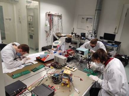 multiple people working on electronics in a clean room