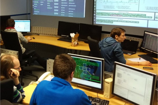 satellite control room with multiple people sitting in front of monitors displaying various data