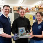 three people holding the assembled FARGO system in a workshop