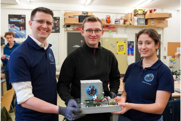 three people holding the assembled FARGO system in a workshop