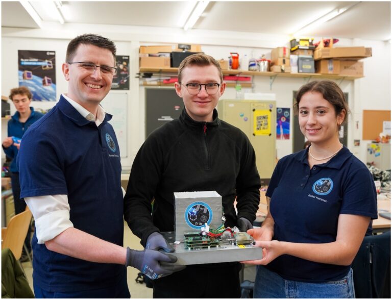 three people holding the assembled FARGO system in a workshop