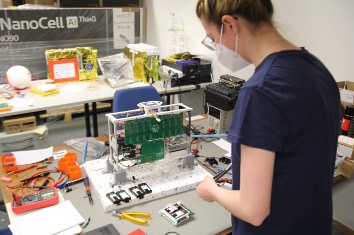 woman in workshop, with plenty of electronics on a table